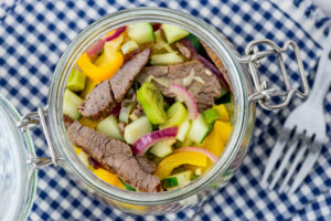 Nahaufnahme, Einmachglas mit Rindfleischsalat auf blauweiß kariertem Tuch. Nahaufnahme, Einmachglas mit Rindfleischsalat auf blauweiß kariertem Tuch.